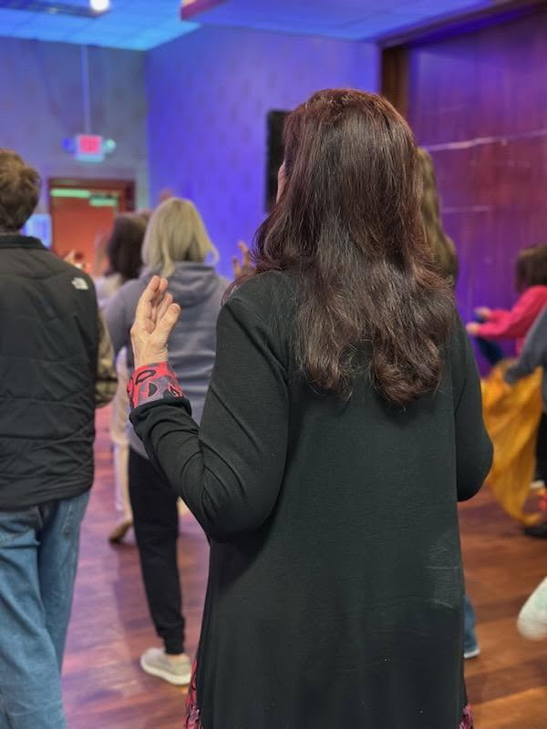 Woman with lifted hand worshipping under purple lights