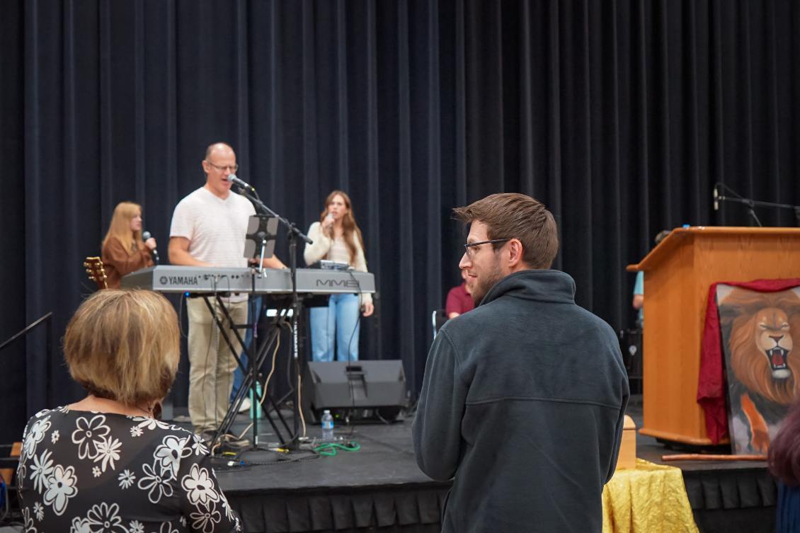 Congregation worshipping as the band plays beside the Lion of Judah painting