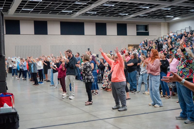 A multitude of worshippers standing with hands raised