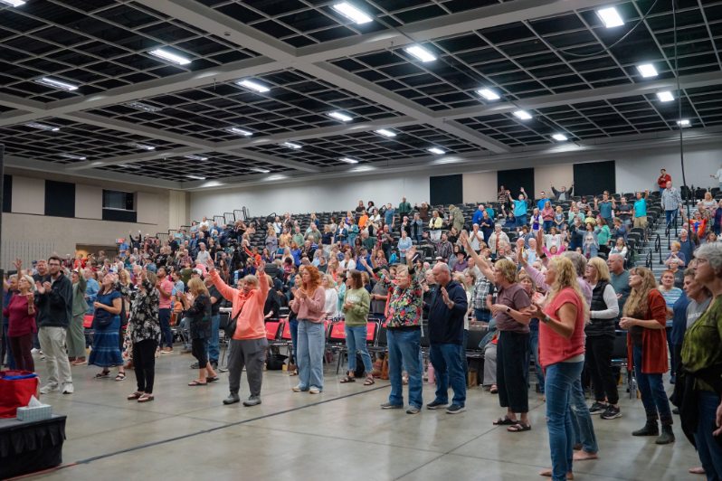 Full congregation standing united in worship with hands raised